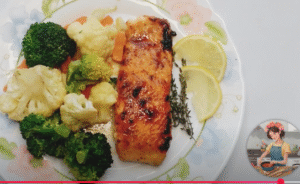 salmon caramelizado emplatado con verduras al vapor, unas rodajas de limon y una ramita de romero