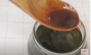se muestra el caramelo cayendo de una cuchara sobre un bote de cristal que contiene el resto del caramelo