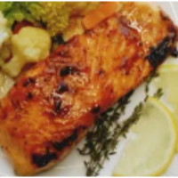 salmon carmelizado servido con verduras al vapor y rodajas de limón