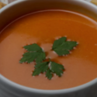 bol de sopa de tomate decorado con una hojita de pereji