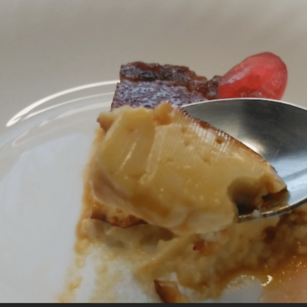 porcion triangular de flan servido en plato blanco con una guinda