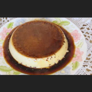 flan redondo cubierto de caramelo dorado en plato de ceramica con flores