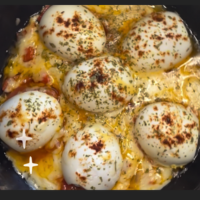 Cada mitad de huevo puesta sobre tomate, con la base de sofrito. Arededor hay queso fundido, y encima se ha espolvoreado pimentón y orégano