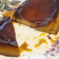 pudin de melocotón en almíbar servido en plato grande y cortado por un extremo, cubierto de caramelo