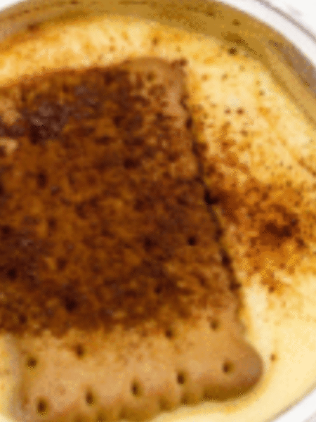 bol lleno de natillas con una galleta encima y canela en polvo