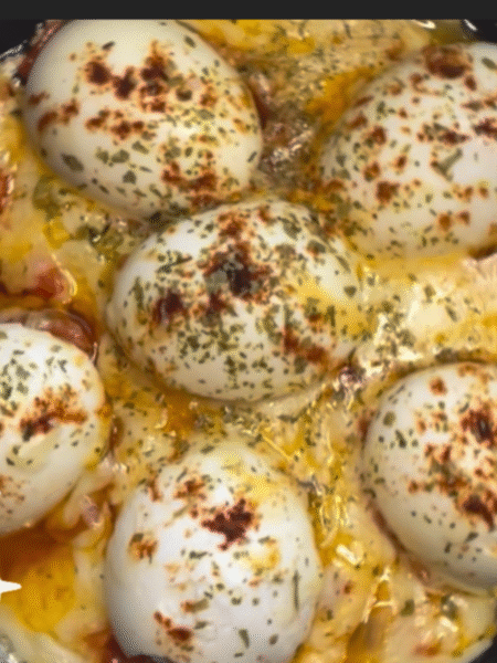 Cada mitad de huevo puesta sobre tomate, con la base de sofrito. Arededor hay queso fundido, y encima se ha espolvoreado pimentón y orégano