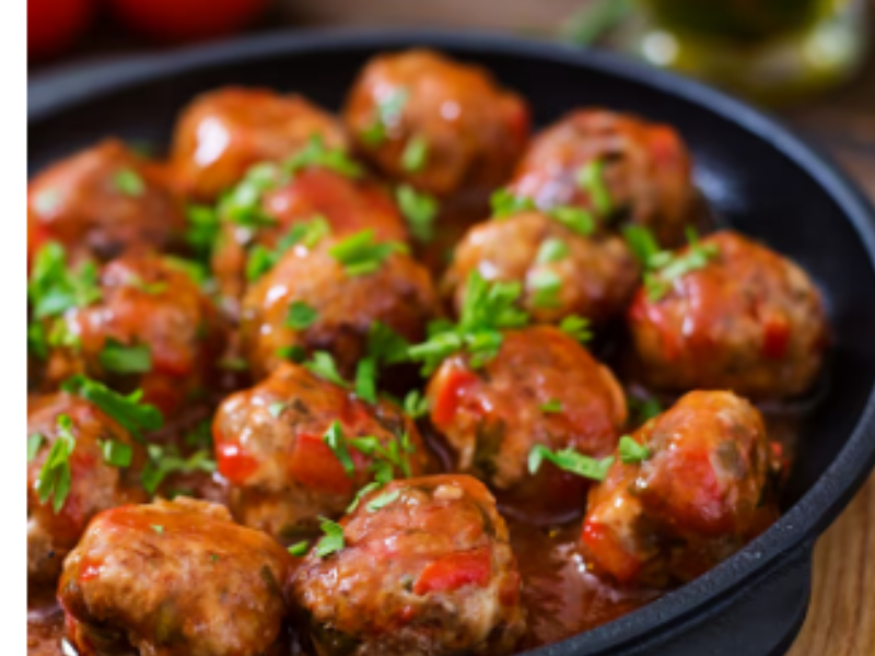 albóndigas en tomate con perejil picado en plato hondo negro