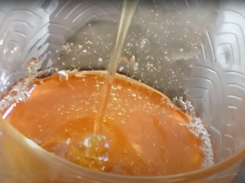 miel de manzana de color ámbar cayendo en hilo en un vaso de cristal que contiene más miel de manzana