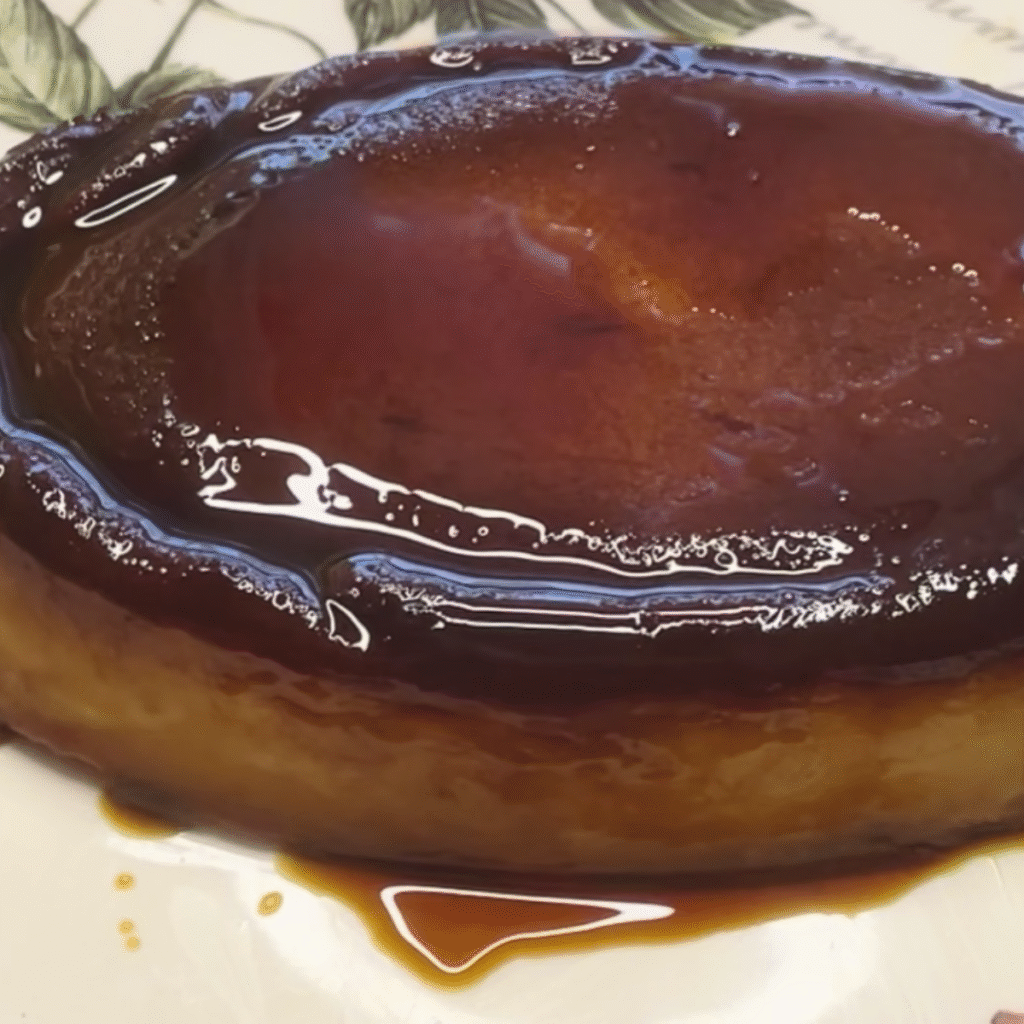 pudin de melocotón en almíbar servido en plato grande y cortado por un extremo, cubierto de caramelo