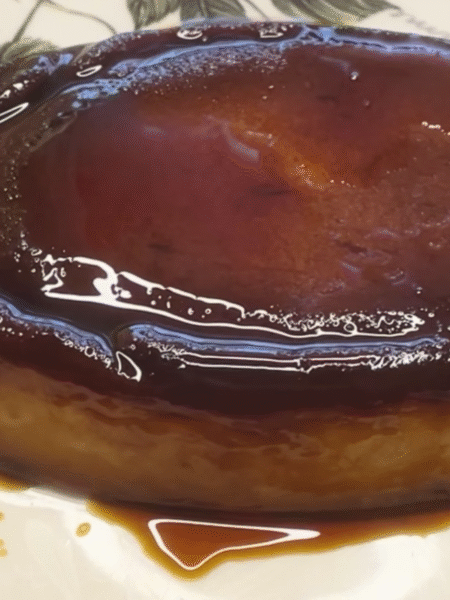 pudin de melocotón en almíbar servido en plato grande y cortado por un extremo, cubierto de caramelo