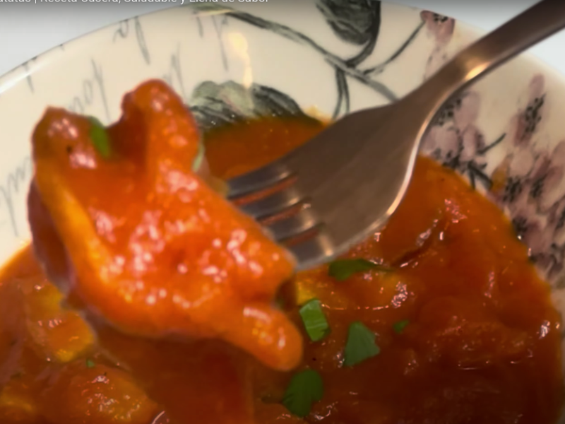 se cogen unas patatas con un tenedor del plato con calabaza con tomate y patatas